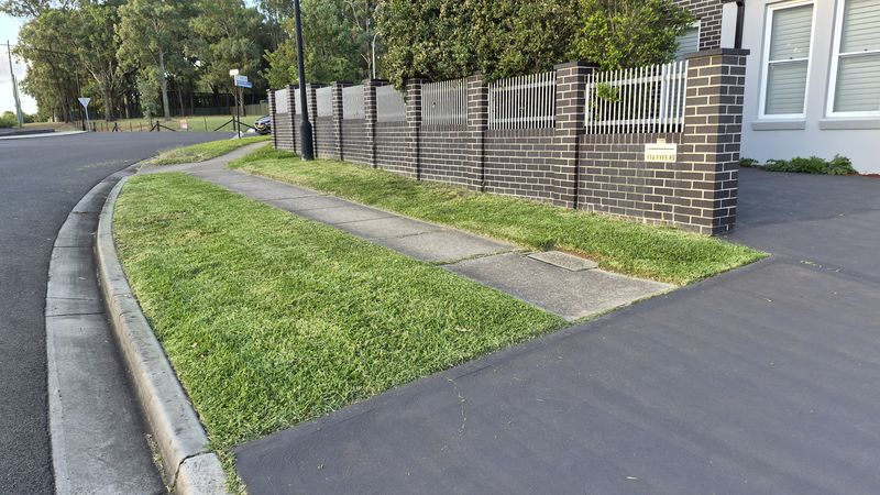 Neatly mowed verge along a commercial estate fence line