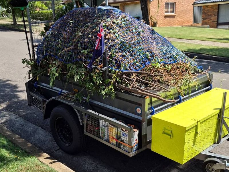 Green With Envy trailer loaded with green waste under a cargo net
